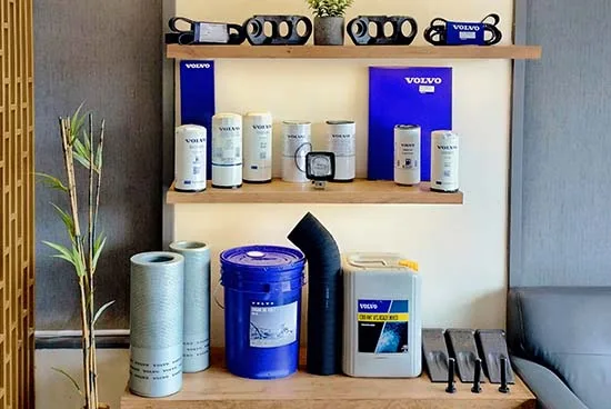 Genuine Volvo spare parts on display — oil and fuel filters, branded lubricant and coolant arranged on wooden shelves.